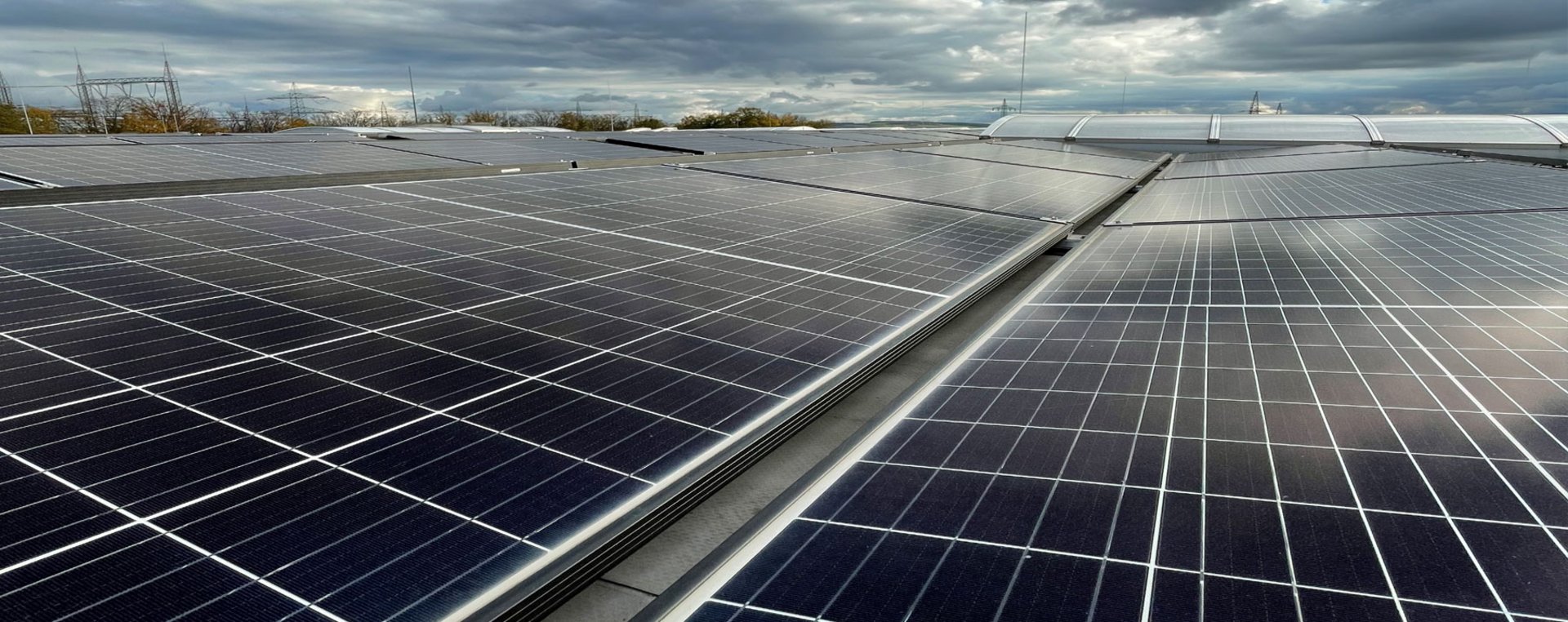 Großes Solarfeld auf einem Industriedach unter bewölktem Himmel, mit Reihen moderner Photovoltaikmodule.
