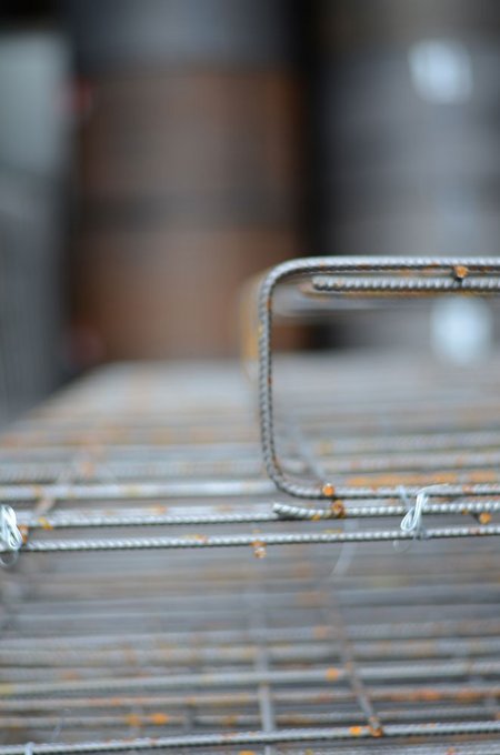 Nahaufnahme einer Bewehrungsmatte aus dünnen, gerippten Stahlstäben, leicht unscharfer Hintergrund.