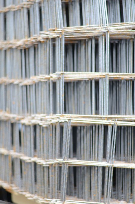 Großaufnahme gestapelter Baustahlmatten mit gerippten Stäben und rostigen Stellen.