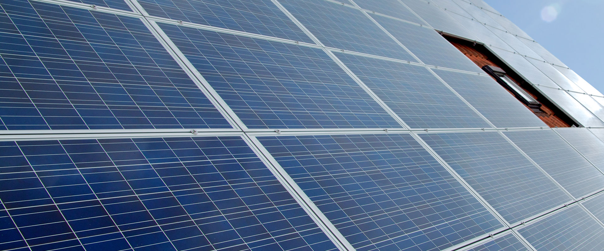 Nahaufnahme einer großflächigen Solaranlage mit blauen Photovoltaikmodulen unter klarem Himmel.