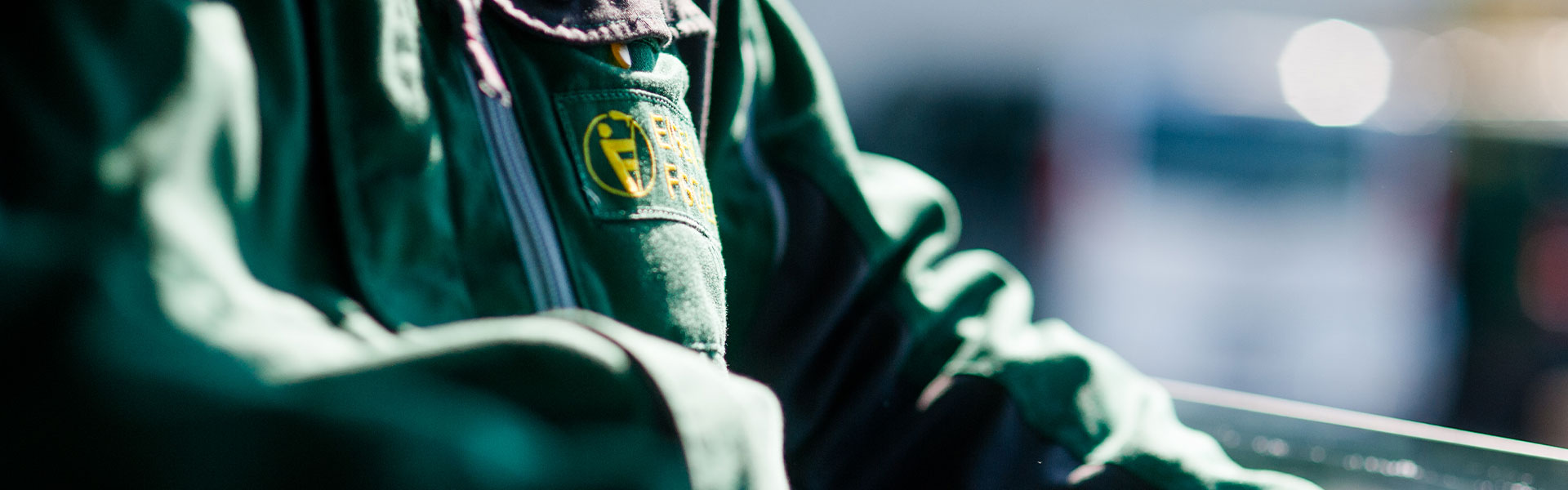 Detailaufnahme einer grünen Arbeitsjacke mit dem aufgestickten Eisen-Fischer-Logo.